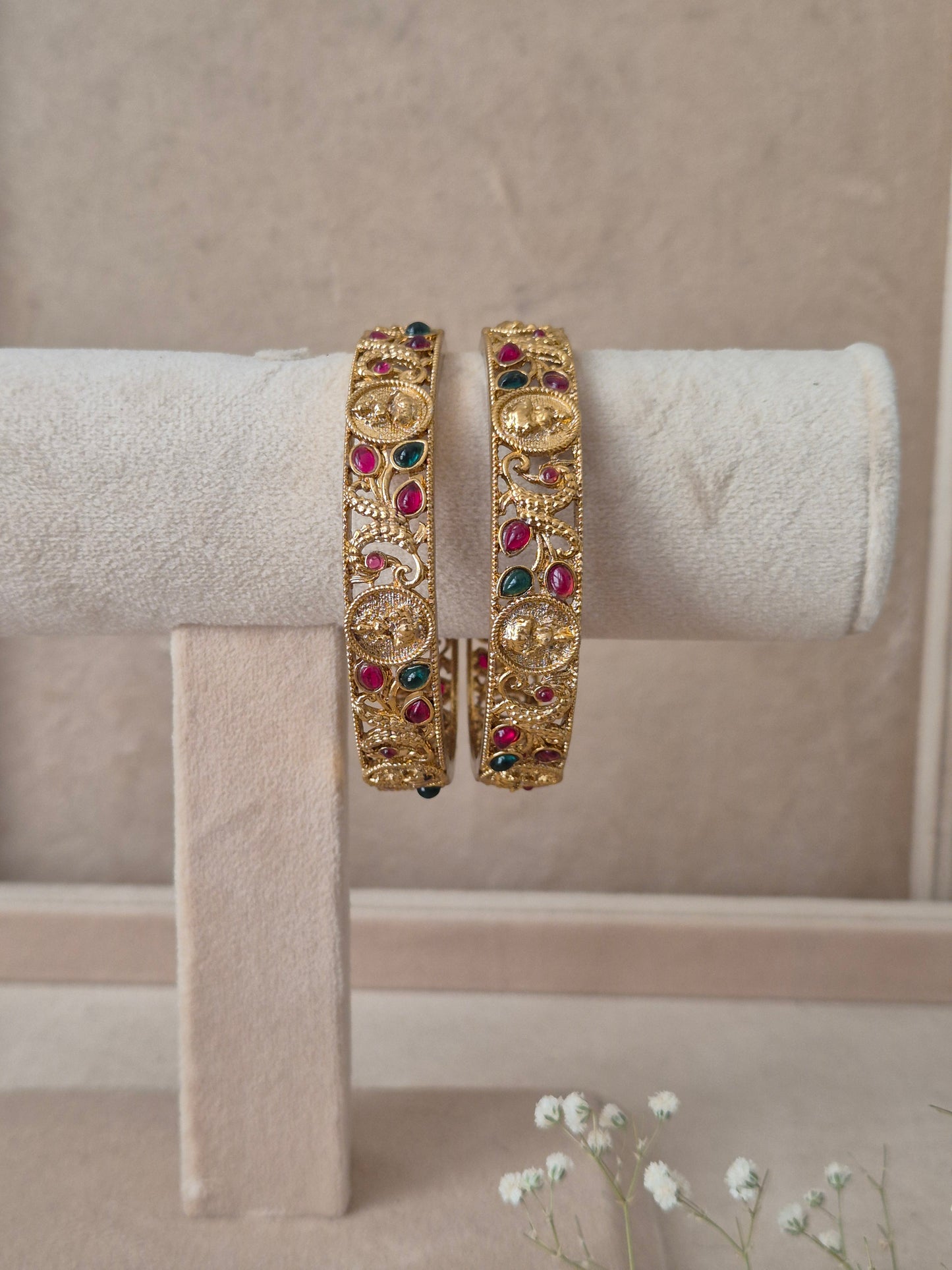 Set of 2 Chirasvi gold bangles by Naitri featuring intricate traditional engravings, accented with alternating ruby-red and emerald-green gemstones, by naitri.in