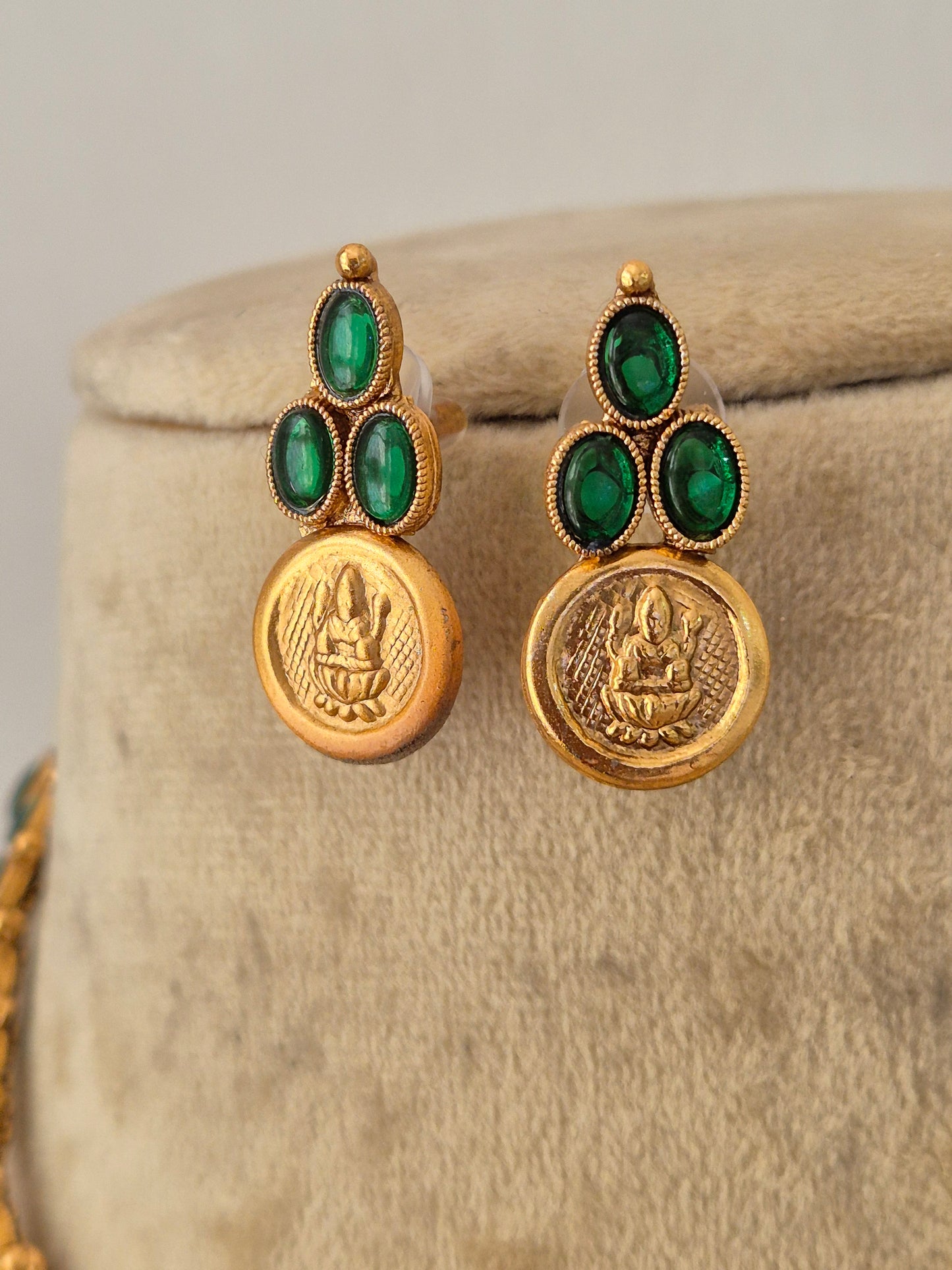 A pair of gold-toned earrings with three green oval stones and a round gold medallion by naitri.in 
