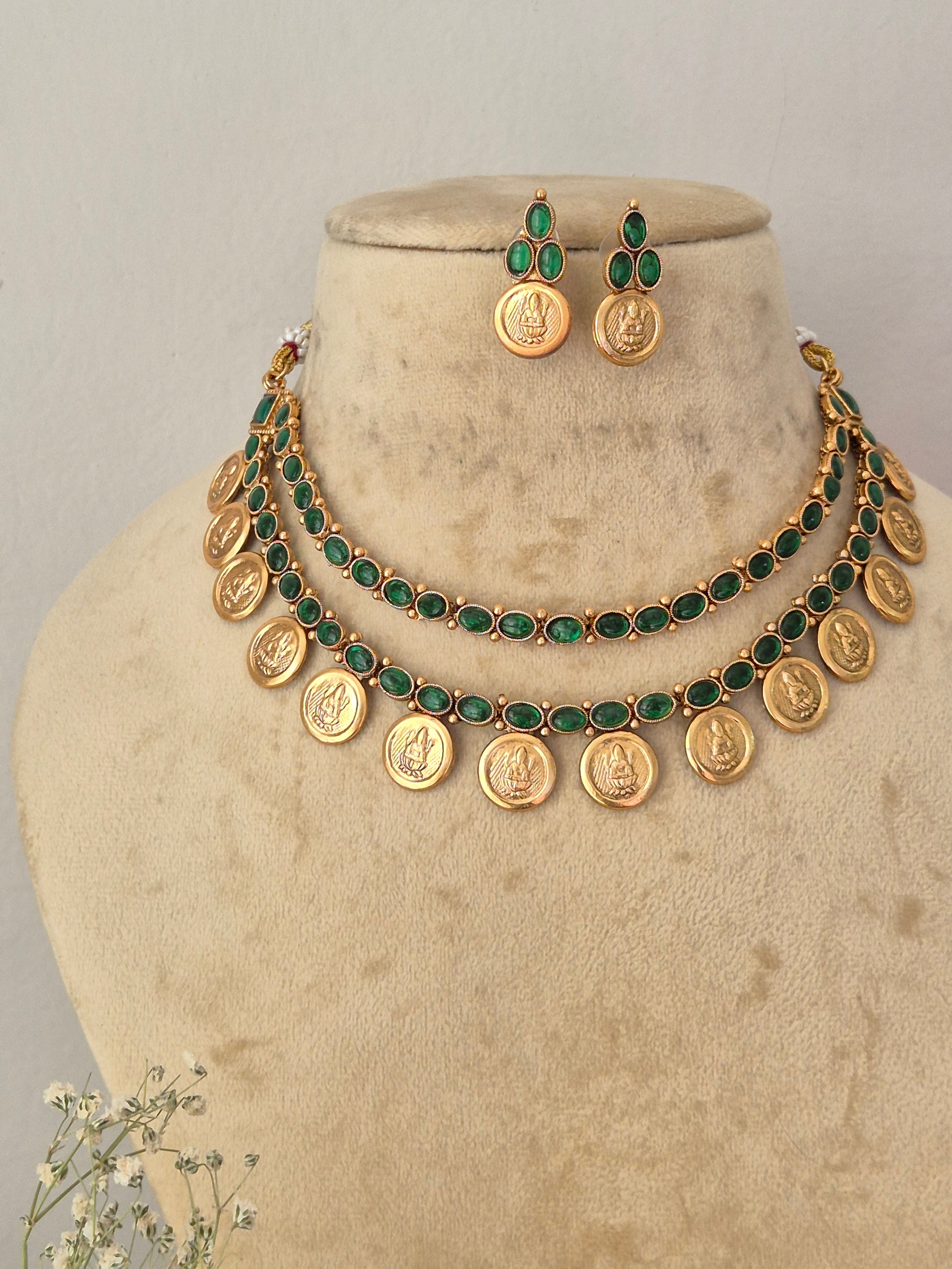 Gold coin necklace and matching drop earrings. The necklace features round gold coin charms linked with dark green stones by naitri.in