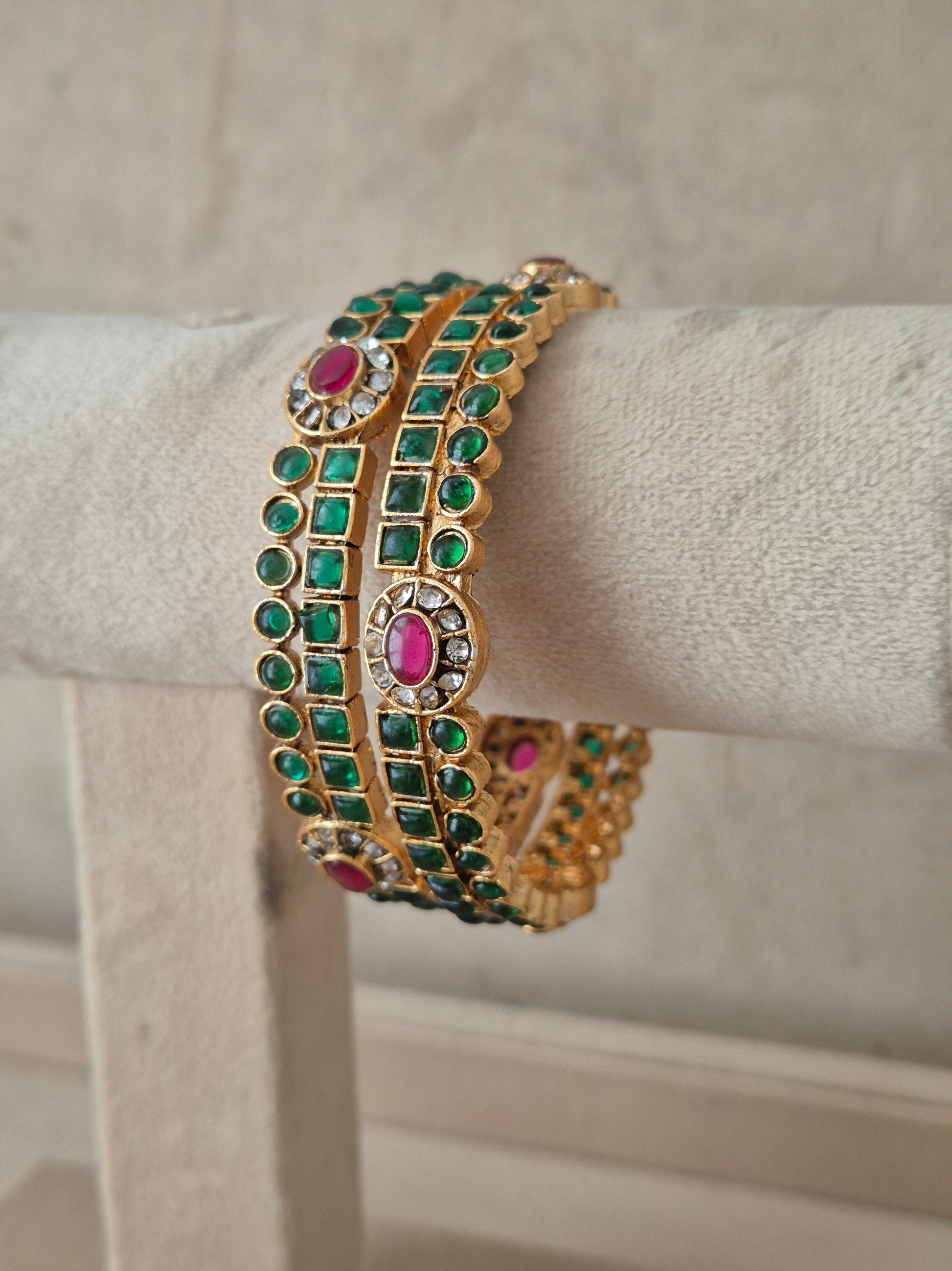 A gold-plated Indian style bangle bracelet with rows of green square-cut stones and pink oval stones, by naitriin