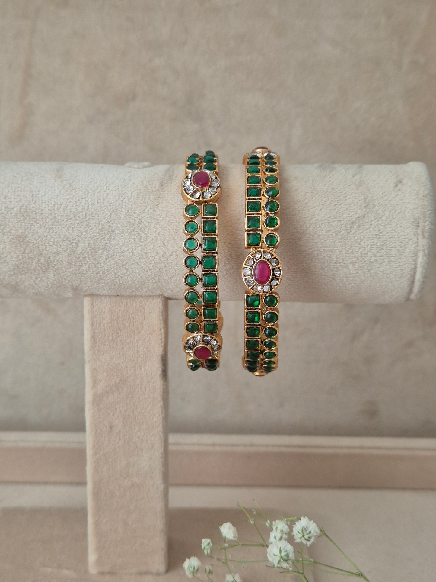 Two gold-plated bangles decorated with green stones and pink oval center stones, by naitri.in
