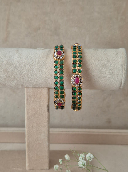 Two gold-plated bangles decorated with green stones and pink oval center stones, by naitri.in
