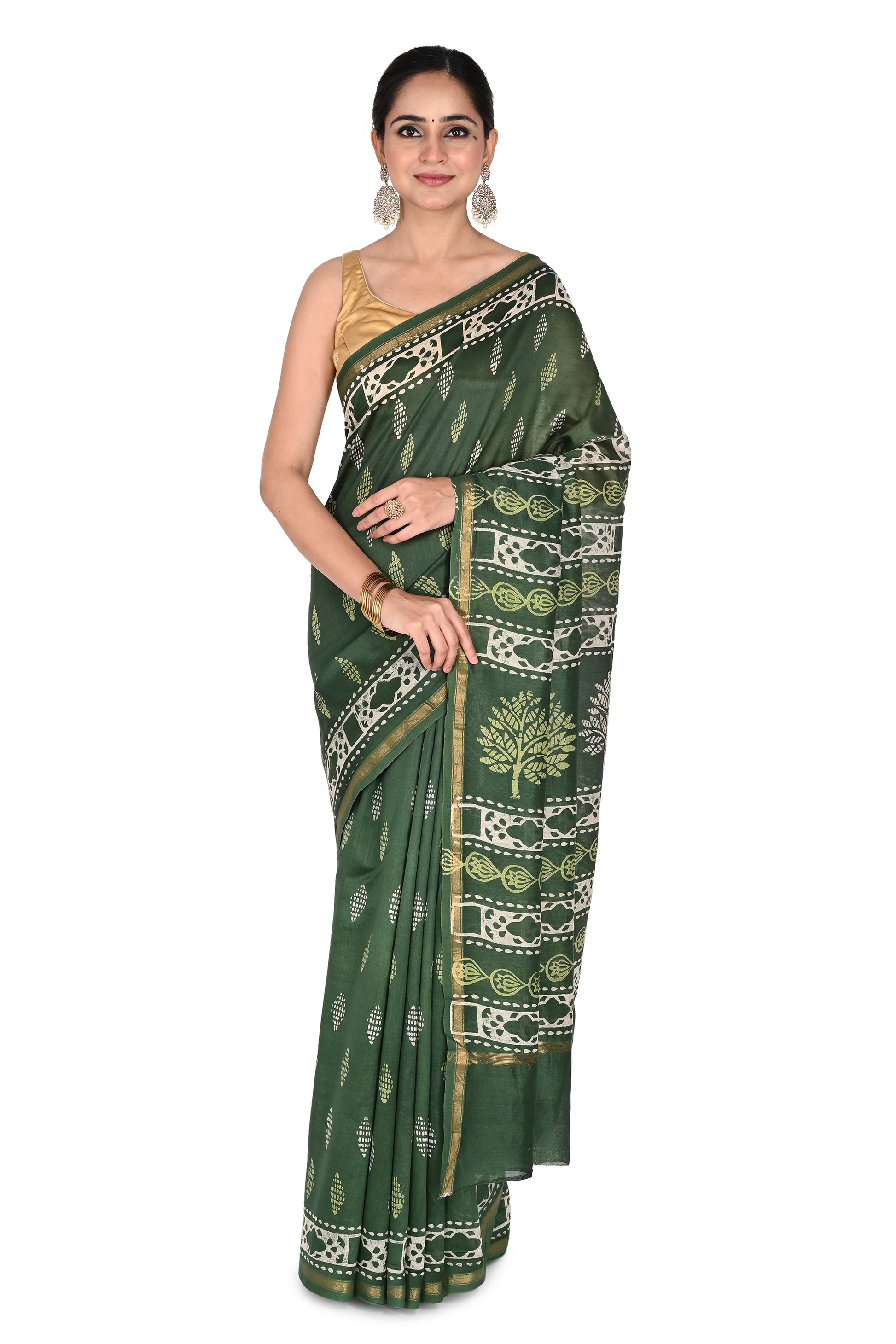 A model wearing the deep green Kimaya cotton-silk saree featuring traditional white hand-block printed tree motifs and a gold zari border, paired with a gold sleeveless blouse by naitri.in