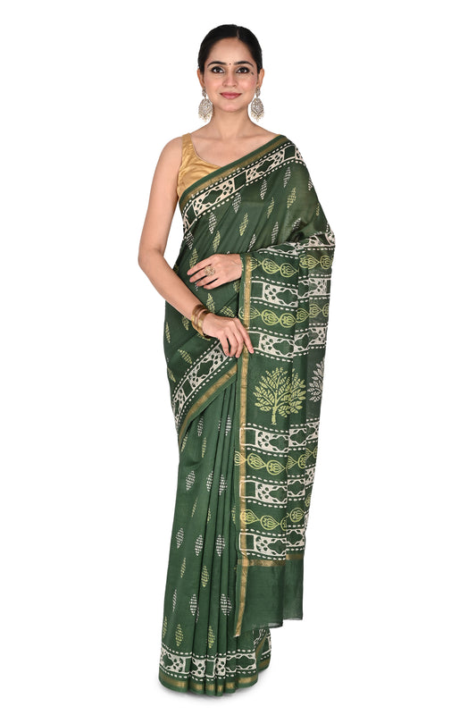A model wearing the deep green Kimaya cotton-silk saree featuring traditional white hand-block printed tree motifs and a gold zari border, paired with a gold sleeveless blouse by naitri.in