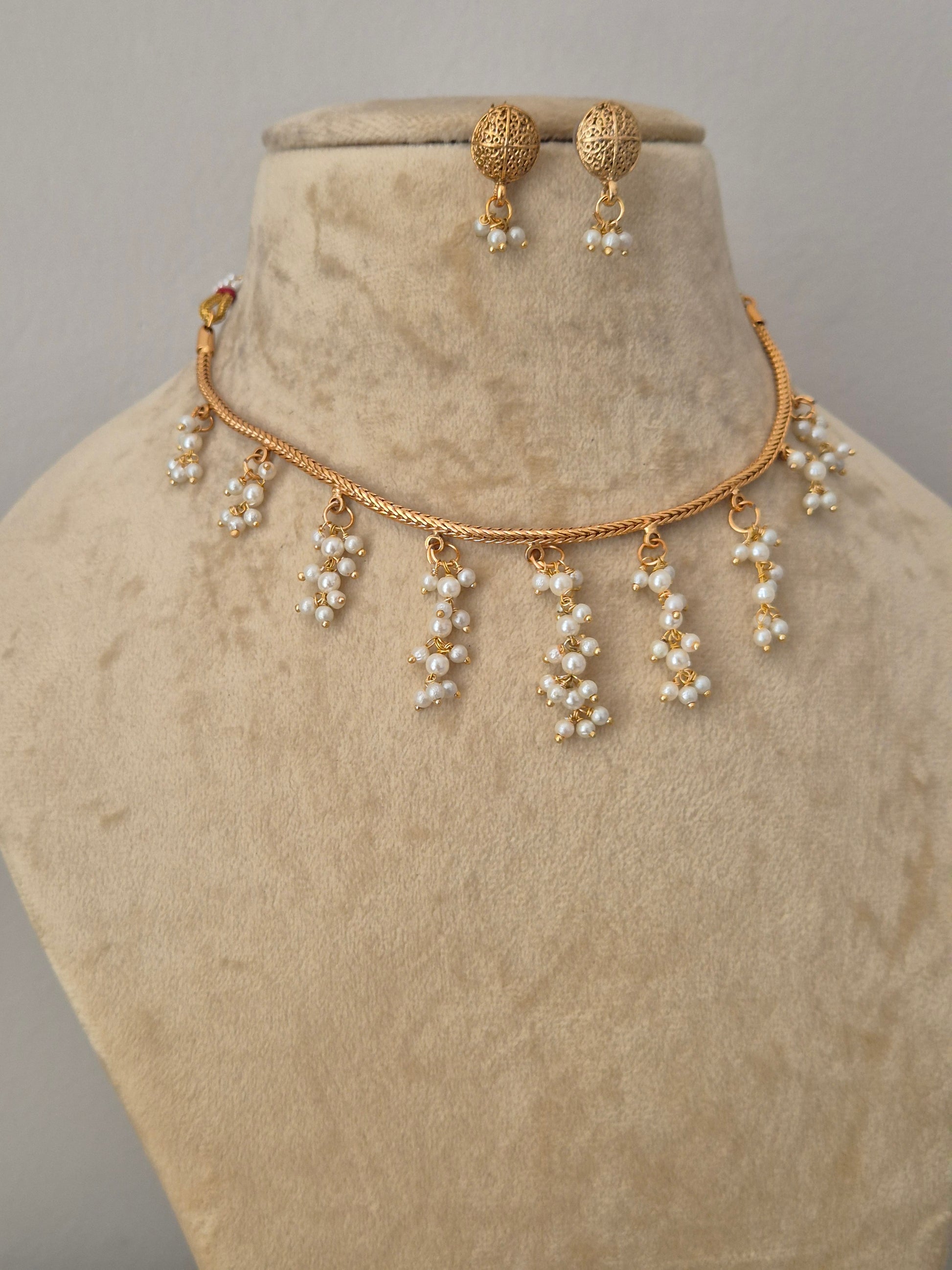 Gold-toned choker necklace and matching drop earrings the necklace features a delicate gold chain with multiple dangling pearl clusters, and the matching earrings have textured gold tops with pearl drops by naitri.in 
