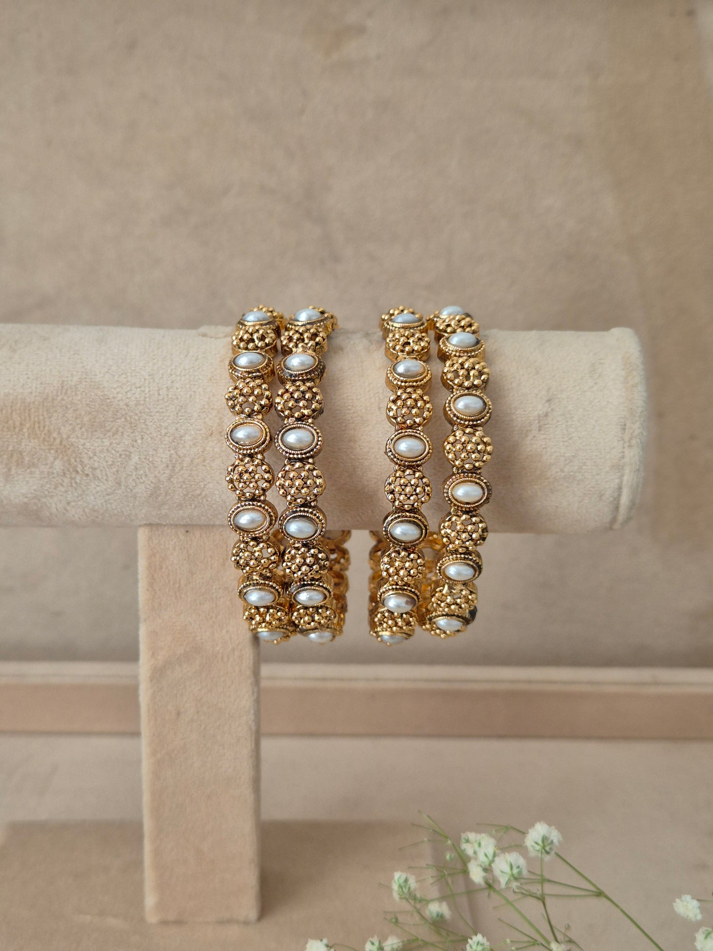 Four gold bangles with intricate filigree, textured gold beads, and faux pearl embellishments, by naitri.in