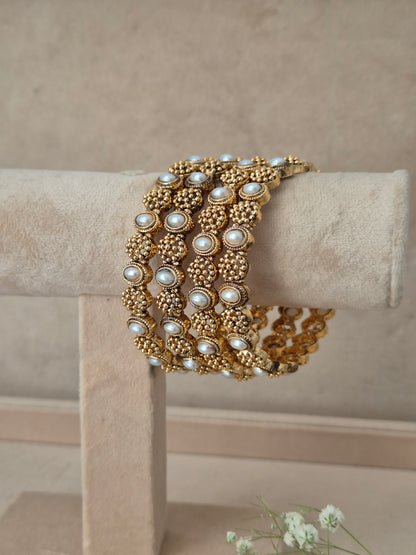 A gold-plated multi-strand bracelet with white faux pearls, by naitri.in