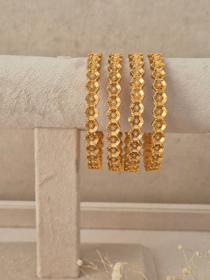 Set of 4 gold-plated bangles featuring an intricate hexagonal grid design and patterned edges by naitri.ijn
