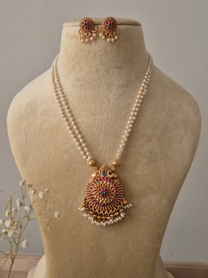 Set featuring a double-strand pearl chain with a large gold-toned circular pendant and matching floral stud earrings by naitri.in