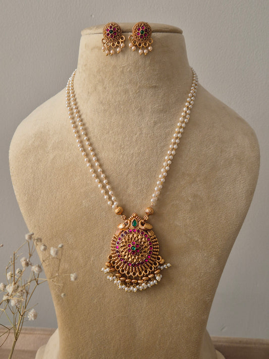 Set featuring a double-strand pearl chain with a large gold-toned circular pendant and matching floral stud earrings by naitri.in