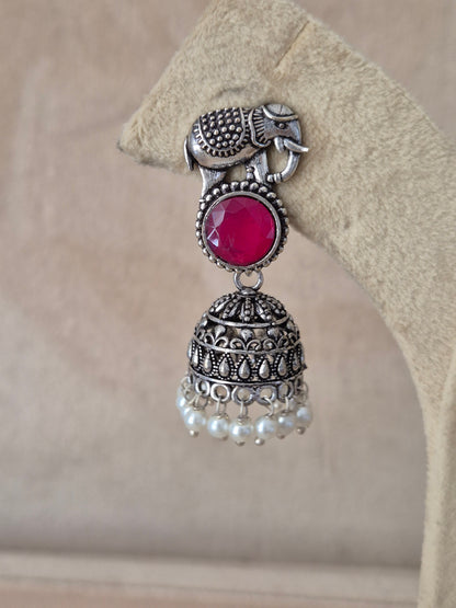 Handcrafted silver Jhumka earrings with vibrant red stones and small pearl beads hanging from an elephant design stud by naitri.in 