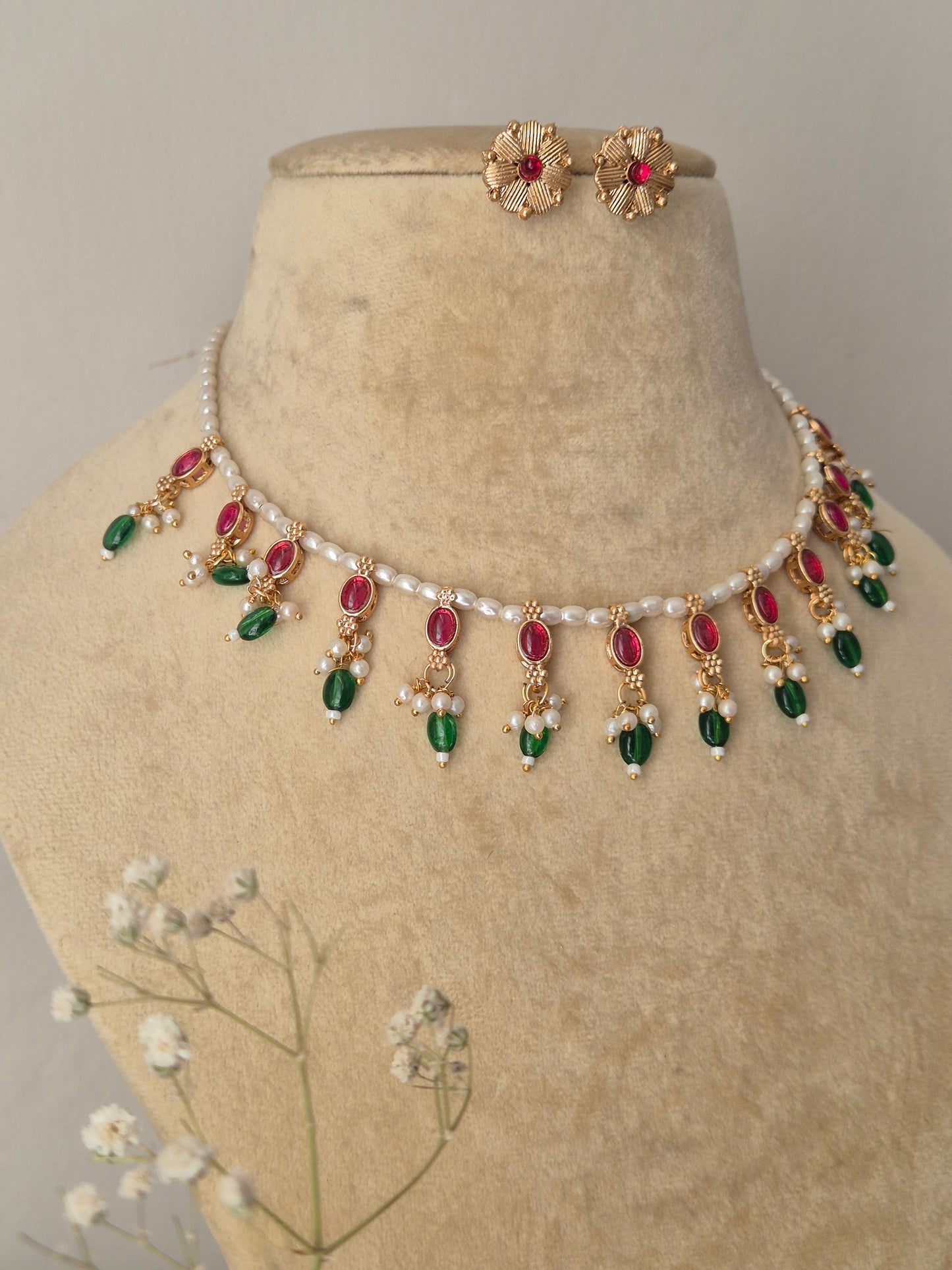 Gold-polished delicate pearl choker with red and green kemp stone embellishments and matching round stud earrings from the Golden Ethnic Jewellery line by naitri.in