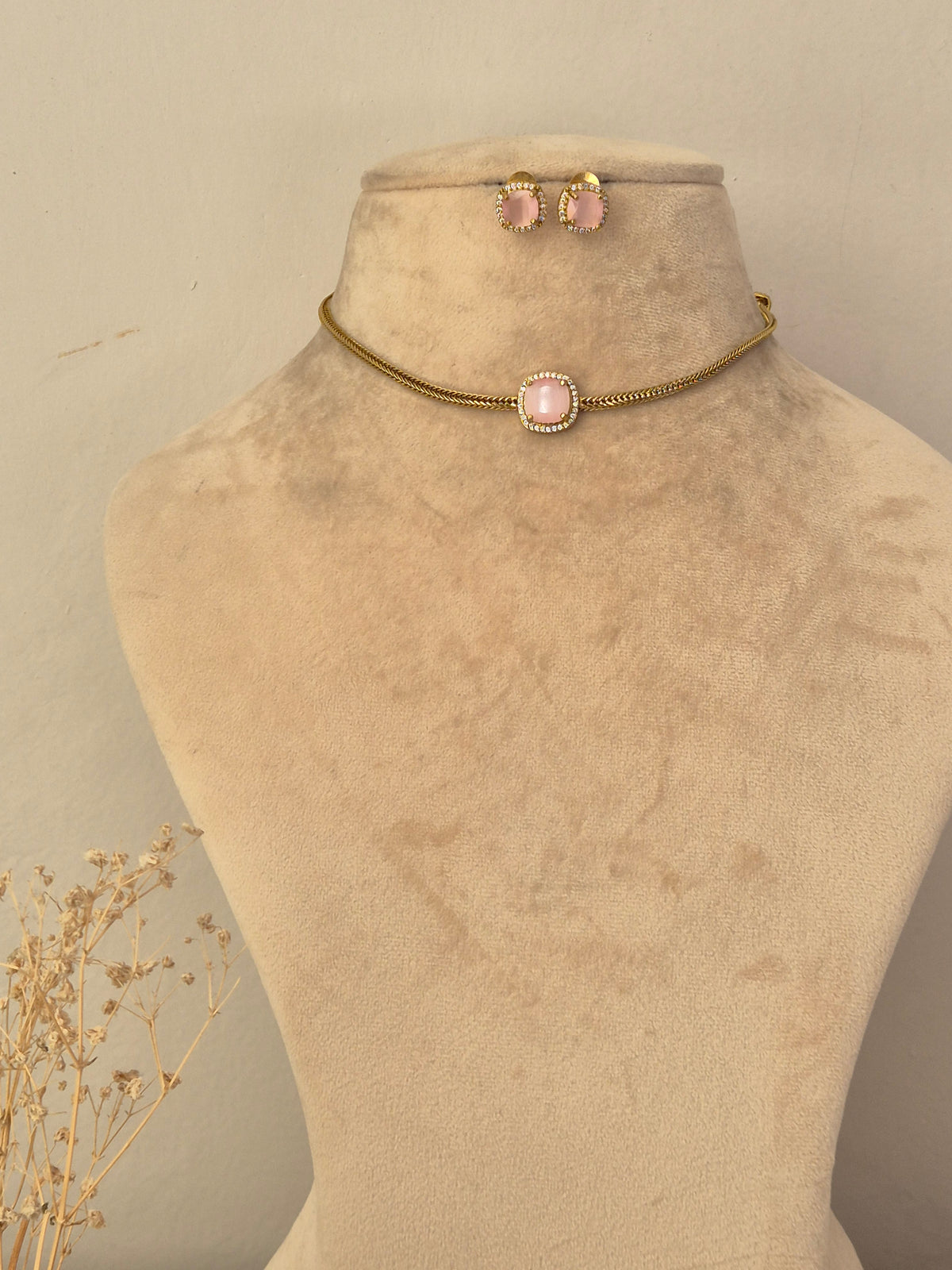 Minimalist gold chain choker featuring a central round blush pink stone surrounded by small crystals with matching oval stud earrings by naitri.in