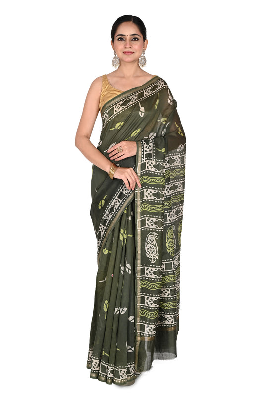 A model wearing an olive green Devyani hand block printed cotton-silk saree with white geometric and paisley patterns, paired with a gold sleeveless blouse by naitri.in
