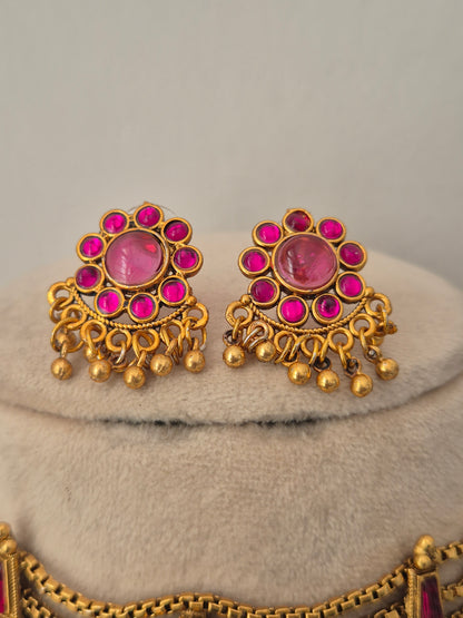 Antique gold-toned earrings intricate metallic round floral vibrant pink stone clusters, and delicate hanging gold bead drops by naitri.in