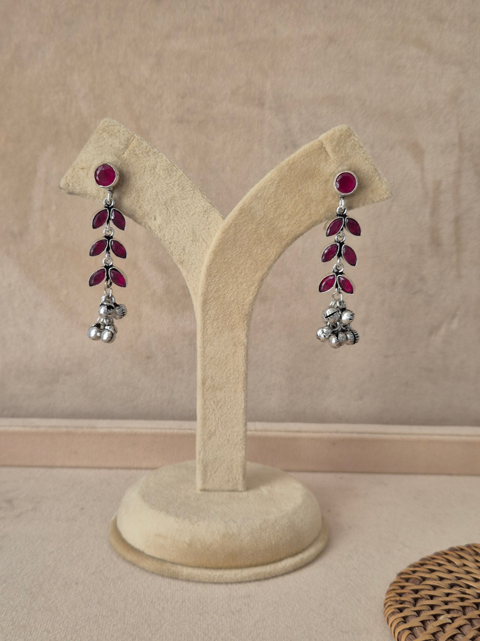 Pair of handcrafted silver-plated dangle earrings with ruby-red stones by naitri.in
