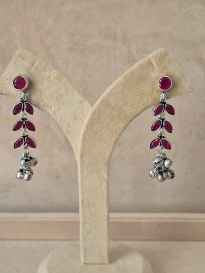 Long silver floral design earrings featuring pinkish-red stone embellishments Elegant Indian traditional dangle earrings with red stones and intricate silver beadwork by naitri.in