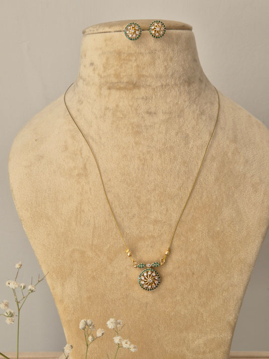Invisible Chain Necklace Set with a circular gold-toned pendant, green stone accents, and matching stud earrings by Naitri.in