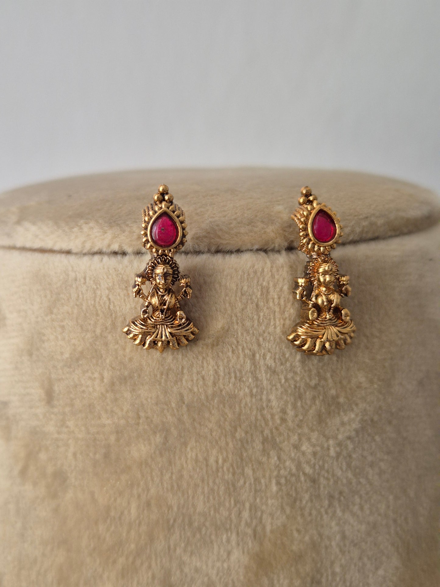 Antique gold-plated earring featuring delicate dangling pendants with tiny ruby-red stone accents, by naitri.in