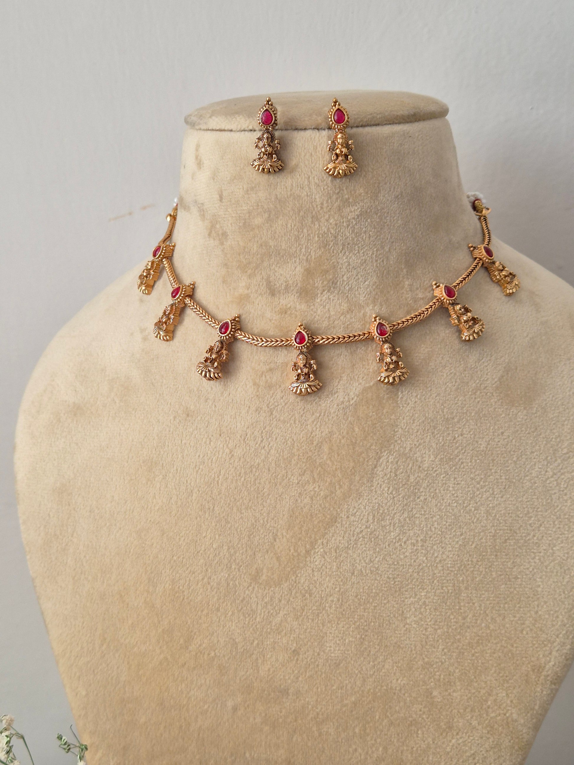 Handcrafted antique gold statement jewelry set showcasing intricate traditional motifs and red gemstone embellishments, ideal for festive styling by naitri.in