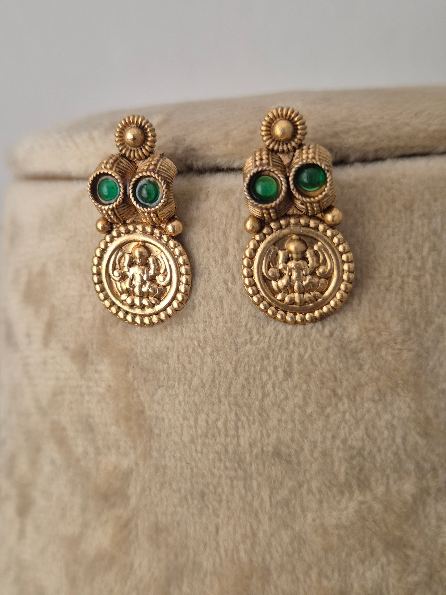 A pair of gold-toned traditional Indian earrings with green stone accents, Traditional Indian gold-toned coin earrings adorned with dark green gemstones by naitri.in