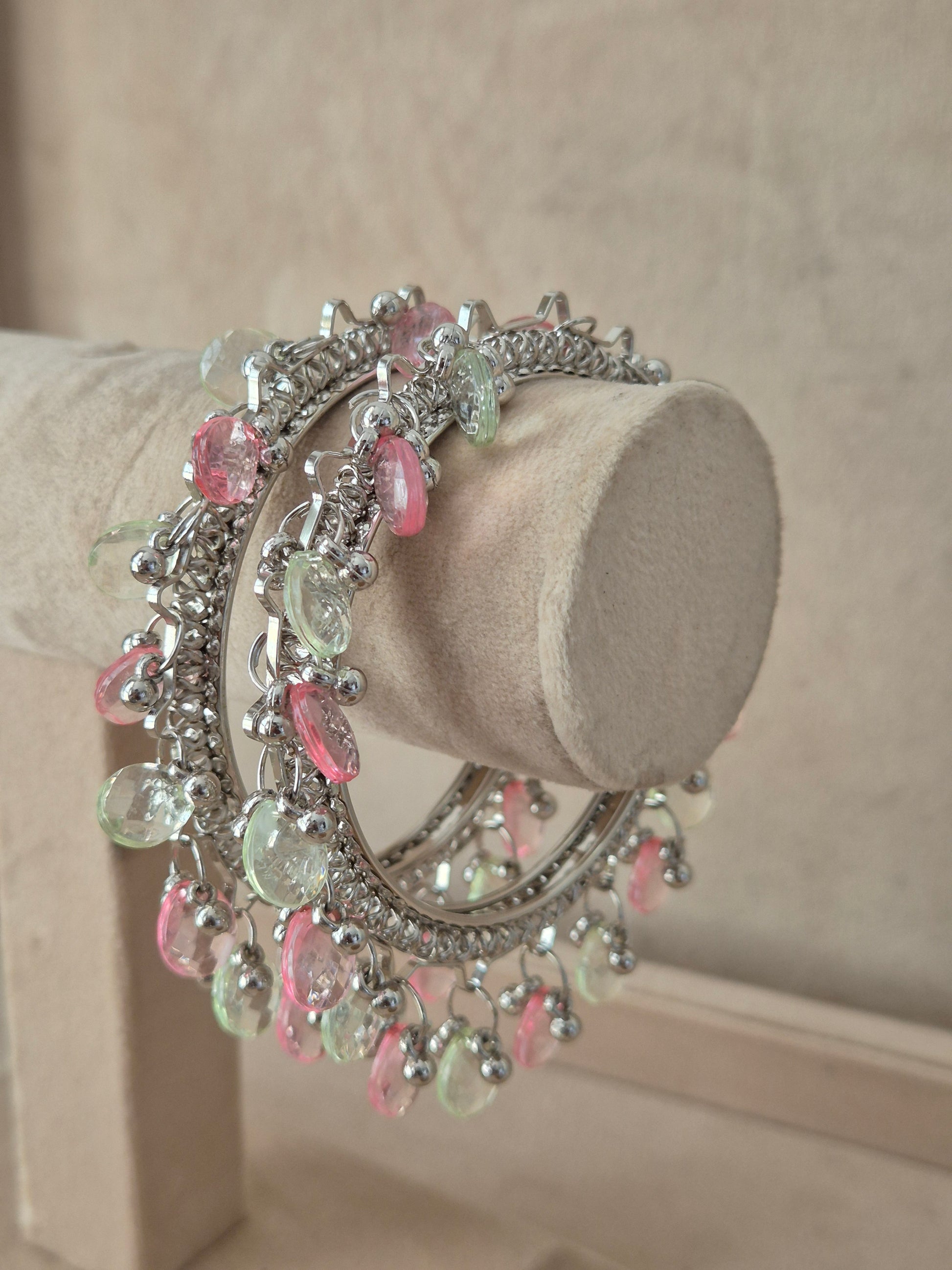 Set of 2 oxidized silver Eartha bangles with dangling pink and green pastel gemstones. Elegant antique silver ethnic bracelets with colorful festive charm details, by naitri.in