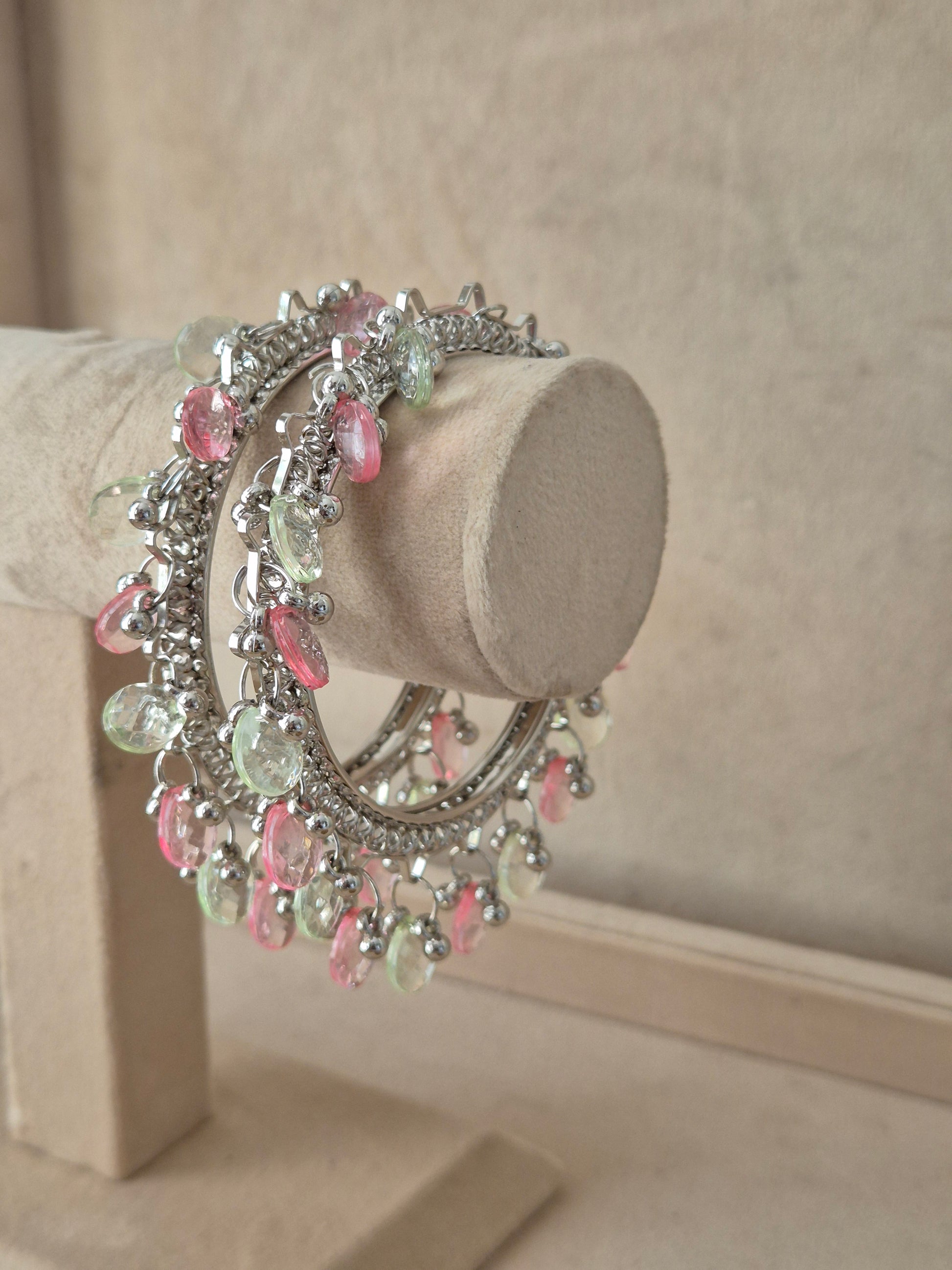 Bohemian-style silver-plated statement bangles adorned with delicate, hanging light pink and green crystal beads by naitri.in
