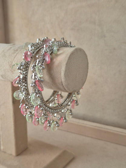 Bohemian-style silver-plated statement bangles adorned with delicate, hanging light pink and green crystal beads by naitri.in