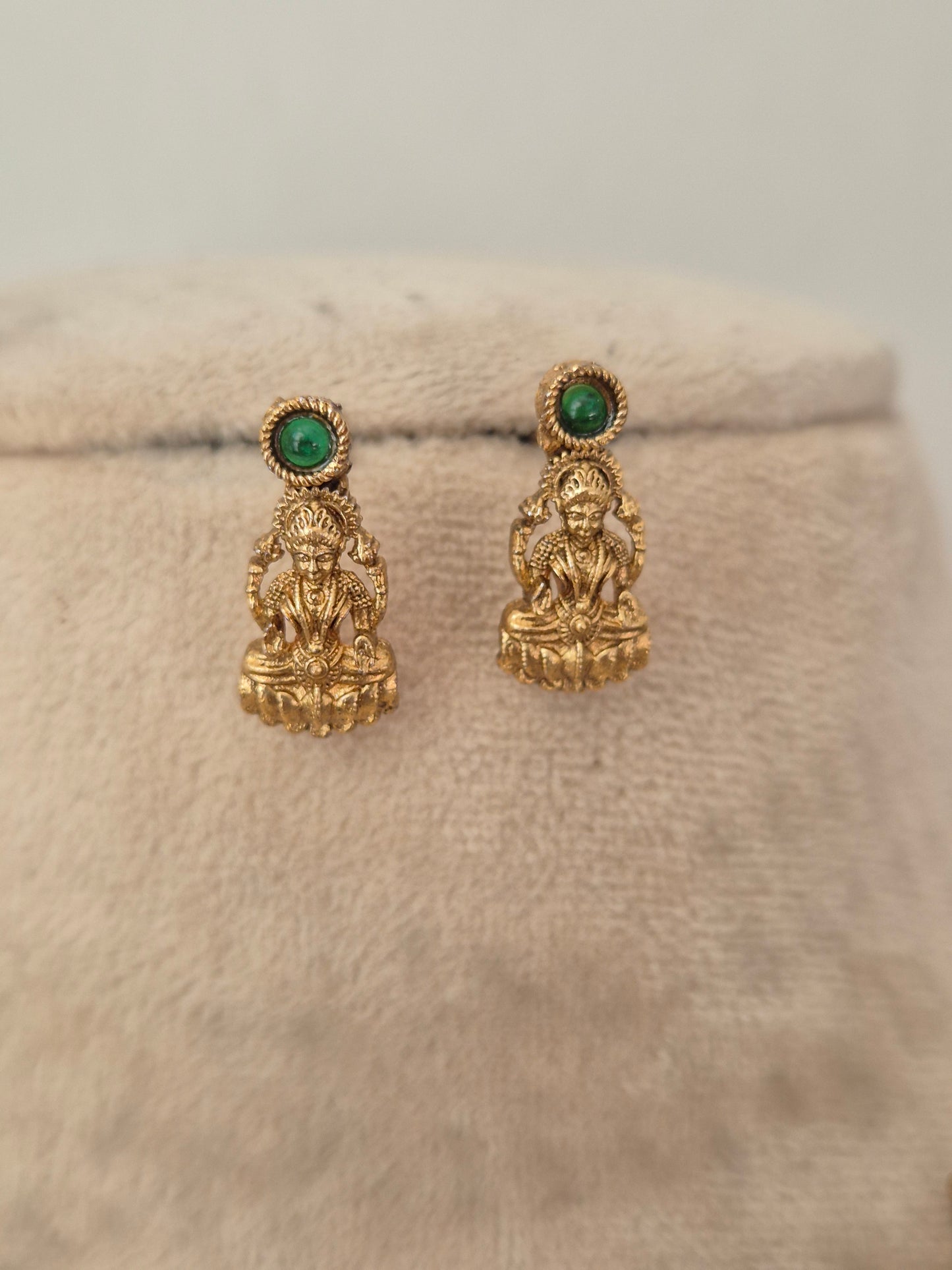 A pair of gold-toned traditional Indian jhumka earrings with round green stone accents, by naitri.in