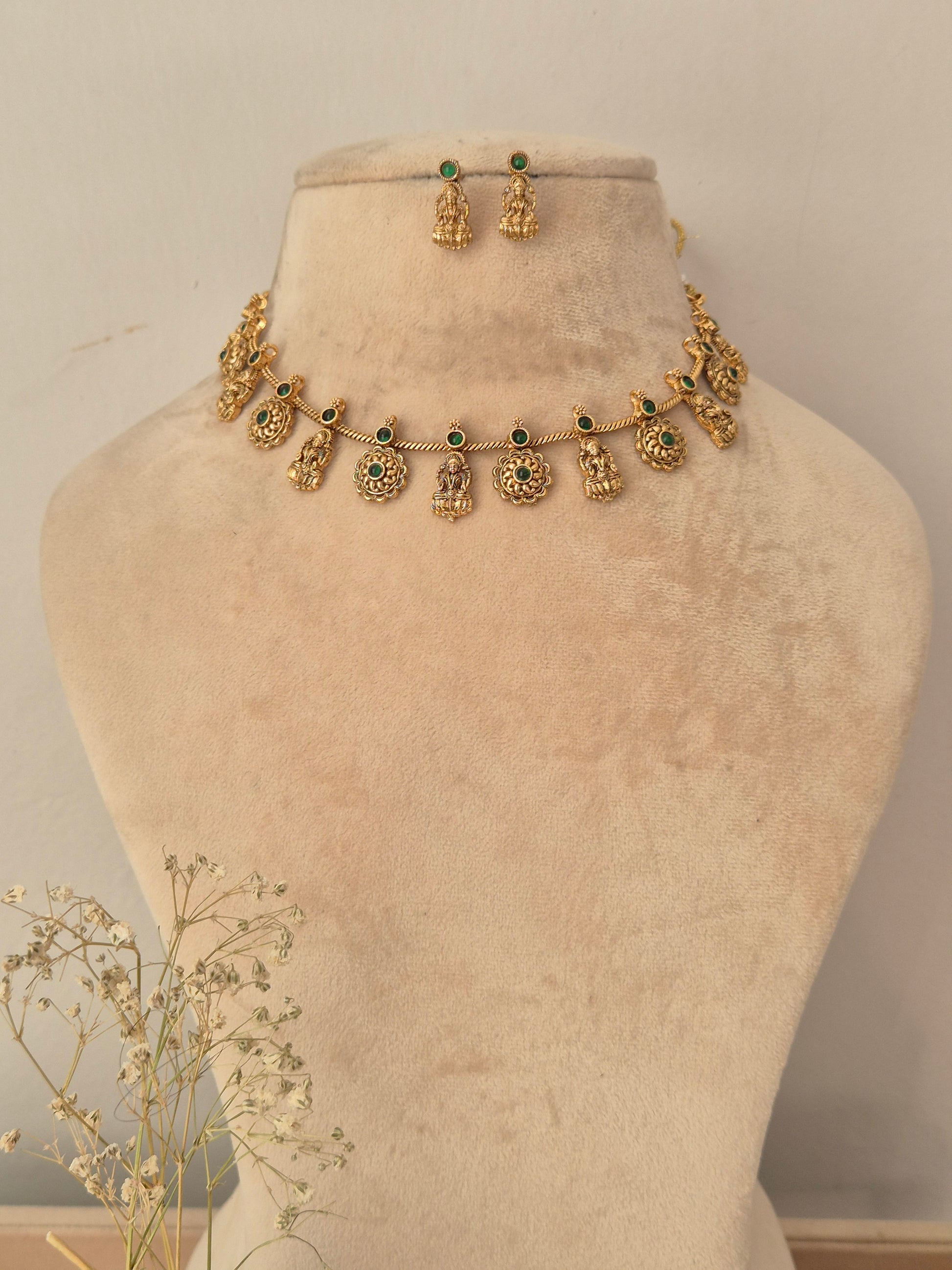 Gold-toned traditional necklace and matching earrings , with small green stone accents and dangling ornate motifs. by naitri.in