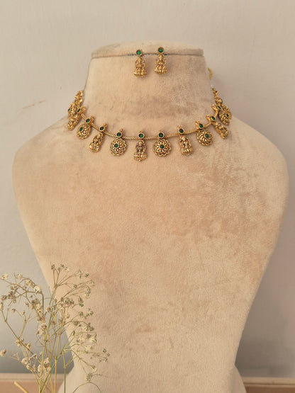 Gold-toned traditional necklace and matching earrings , with small green stone accents and dangling ornate motifs. by naitri.in