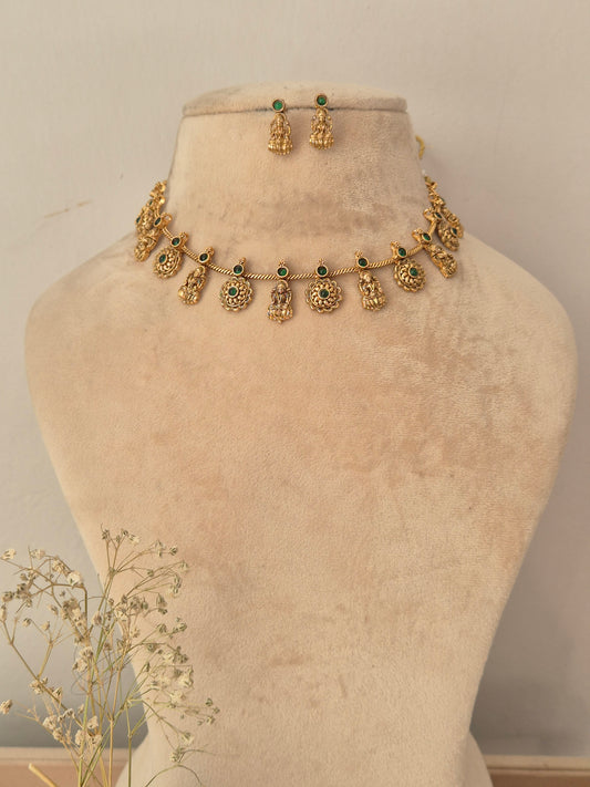 Gold-toned traditional necklace and matching earrings , with small green stone accents and dangling ornate motifs. by naitri.in