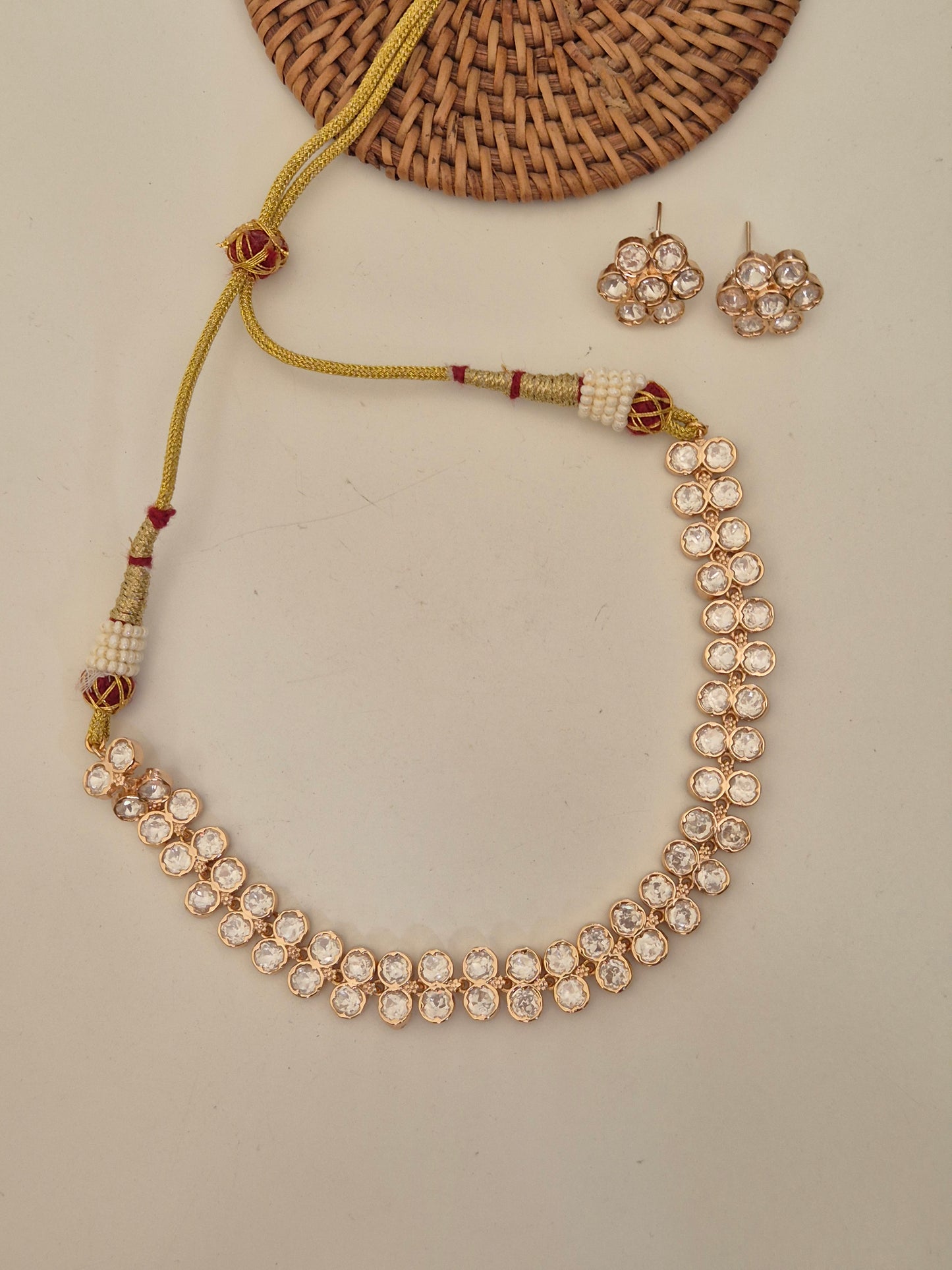 Elegant rose-gold necklace with two rows of oval-shaped clear crystals, set featuring sparkling AD stones and A timeless handcrafted delicate floral earring design by naitri.in