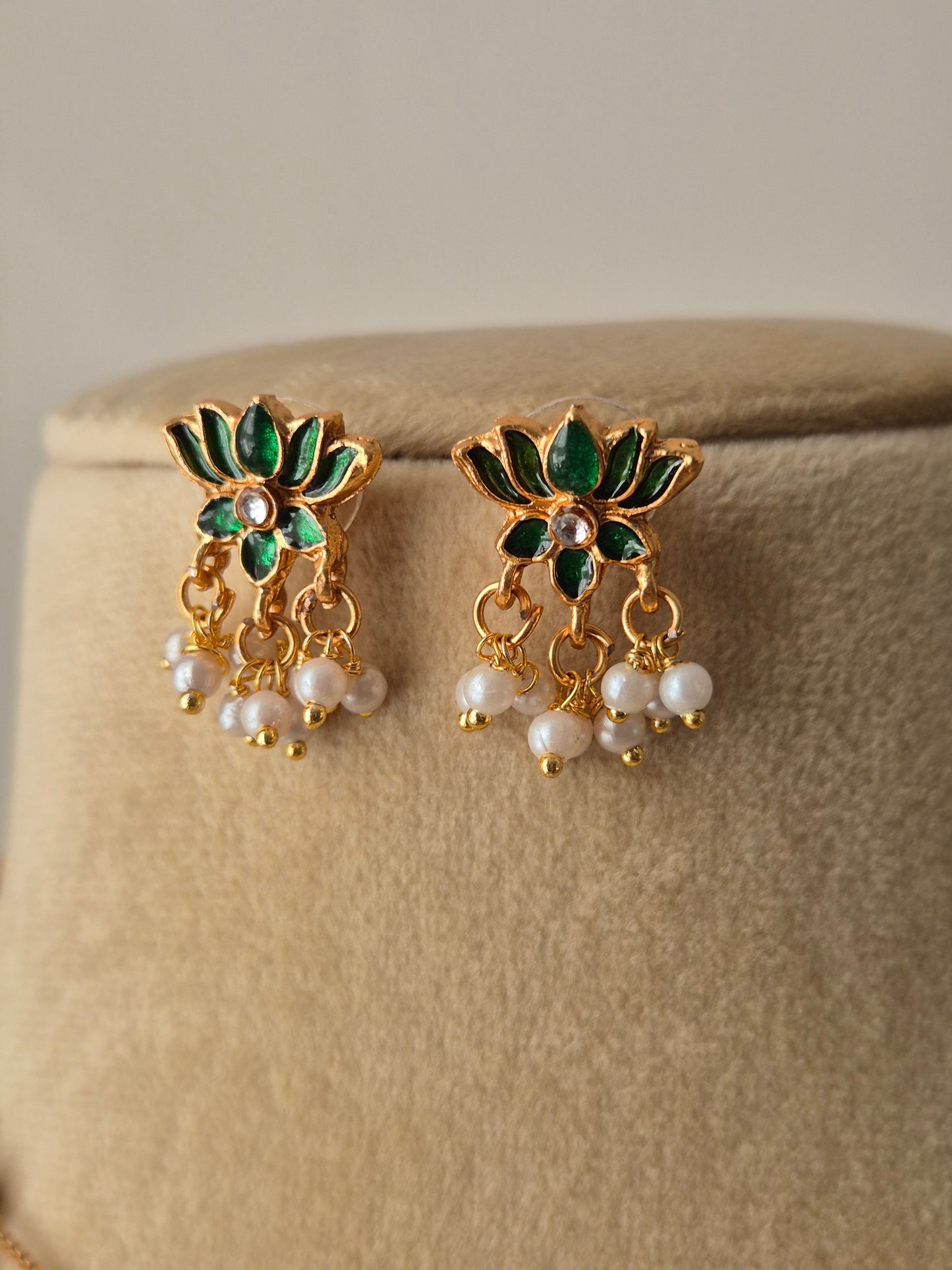 Pair of gold earrings with green petals and leaves and white pearls a small stone in the middle minimal and aesthetic design by naitri.in 