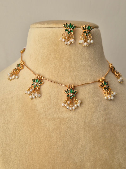 Jewelry set with green and gold elements with Pair of gold earrings with green petals and leaves, a small stone in the middle and white pearls drop by naitri.in
