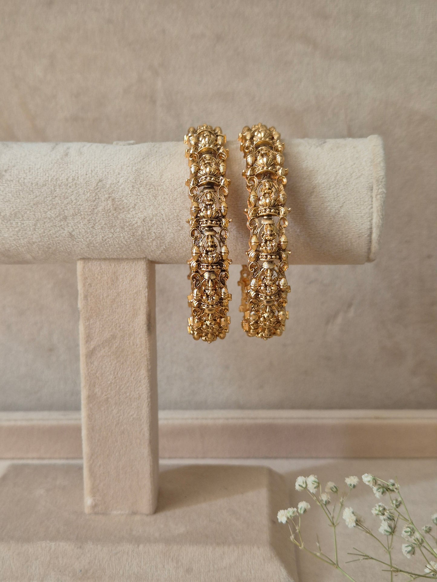 A set of two gold-plated Ema bangles featuring intricate traditional metalwork engraving and a textured finish by naitri.in