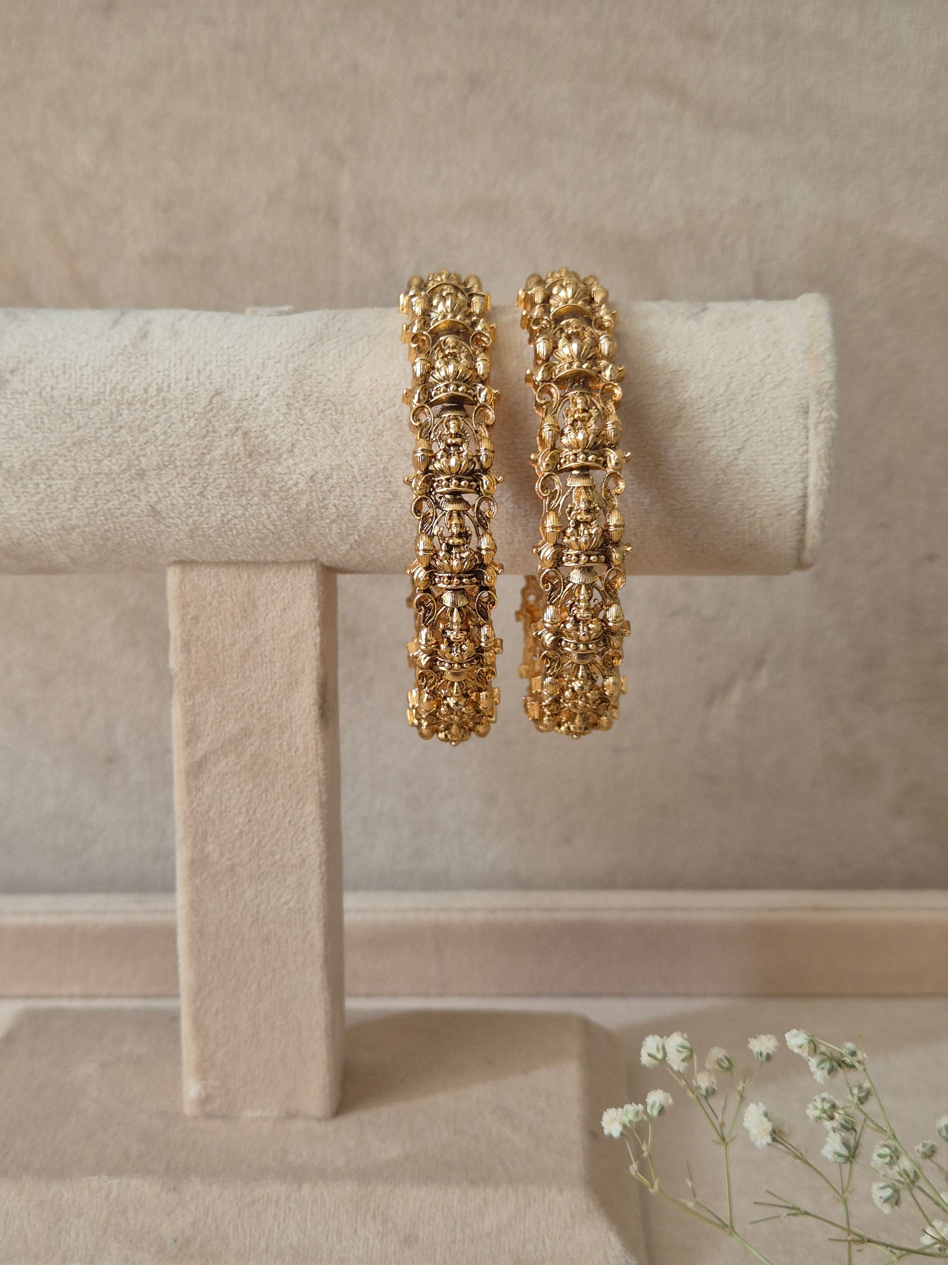 A set of two gold-plated Ema bangles featuring intricate traditional metalwork engraving and a textured finish by naitri.in
