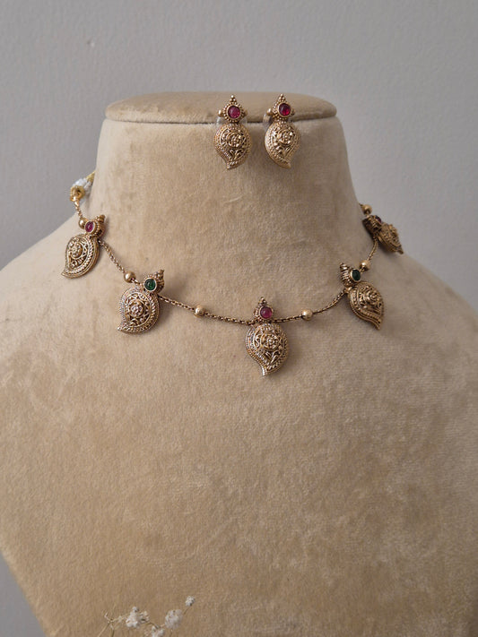 Handcrafted gold necklace and earring set with red and green gemstone embellishments on a minimalist chain by naitri.in