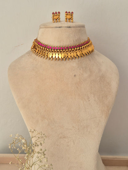 A gold-toned traditional choker necklace with a row of pink stones, Matching gold earrings with pink stones by naitri.in