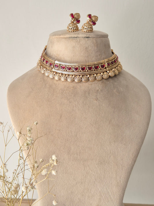 Handcrafted gold-plated brass choker necklace with intricate red stone embellishments and matching jhumka earrings by naitri.in