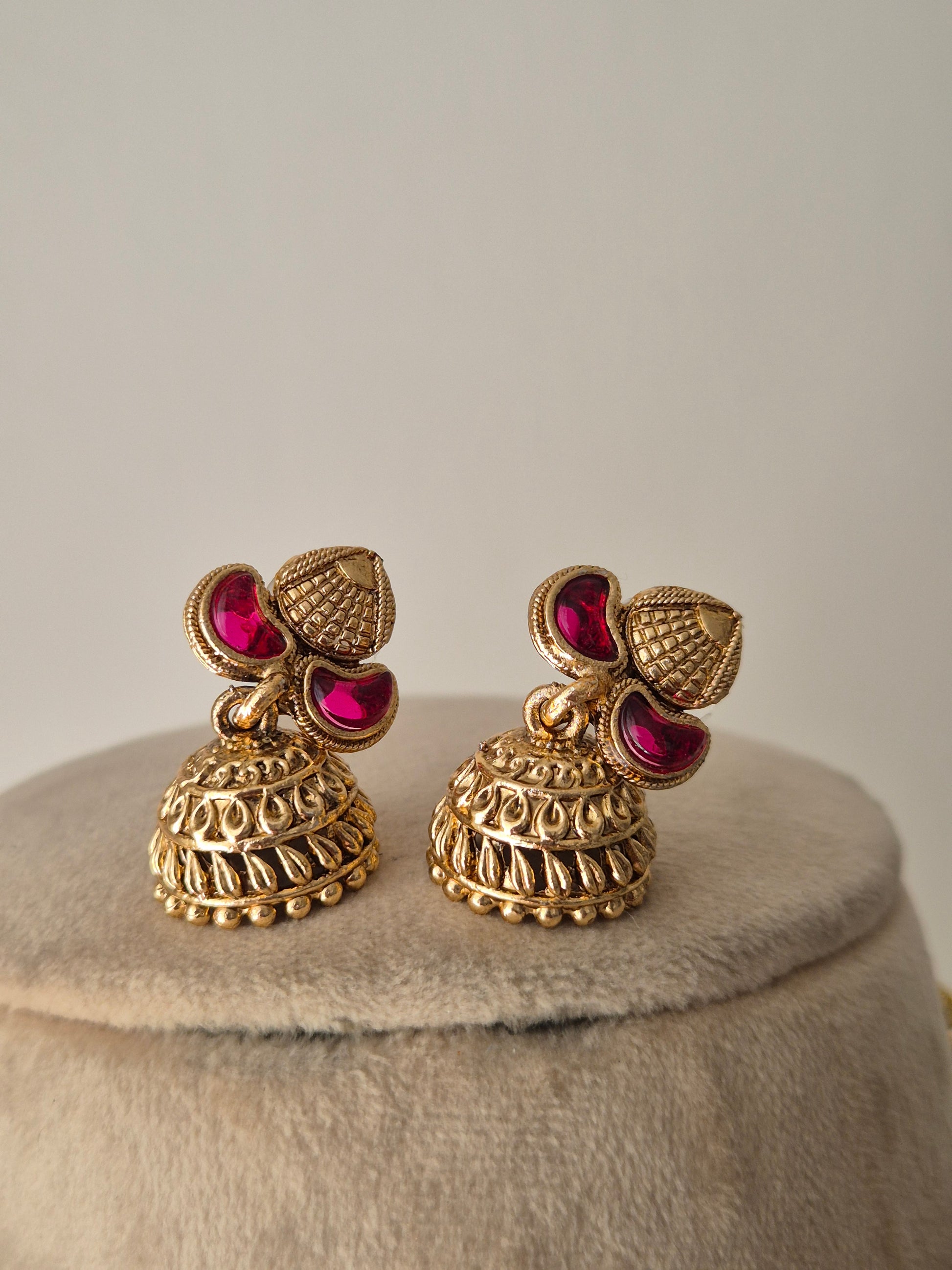 Antique gold earring set with ruby-colored stone accents by naitri.in