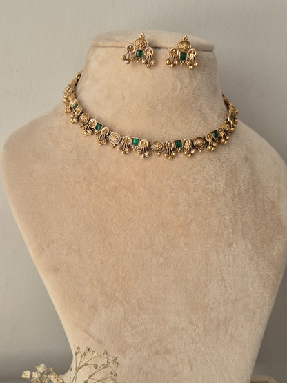 Gold-toned traditional jewelry set including a choker necklace and matching earrings with green stone accents by naitri.in