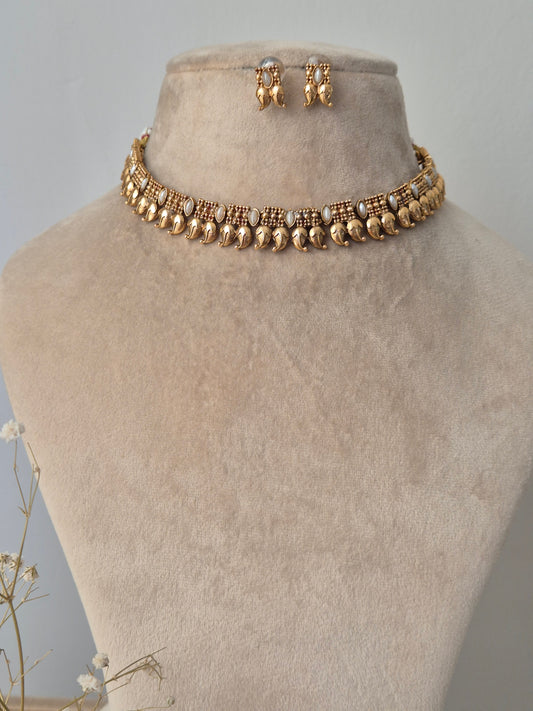 Gold necklace with leaf drop design attached fir gold plated chain and white stones attached in chain same designed earrings by naitri.in