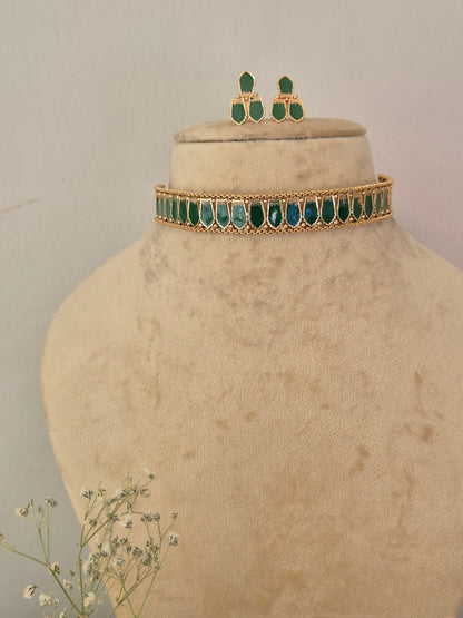 Gold-toned jewelry set, featuring a choker-style necklace with green teardrop-shaped stones and matching drop earrings by naitri.in