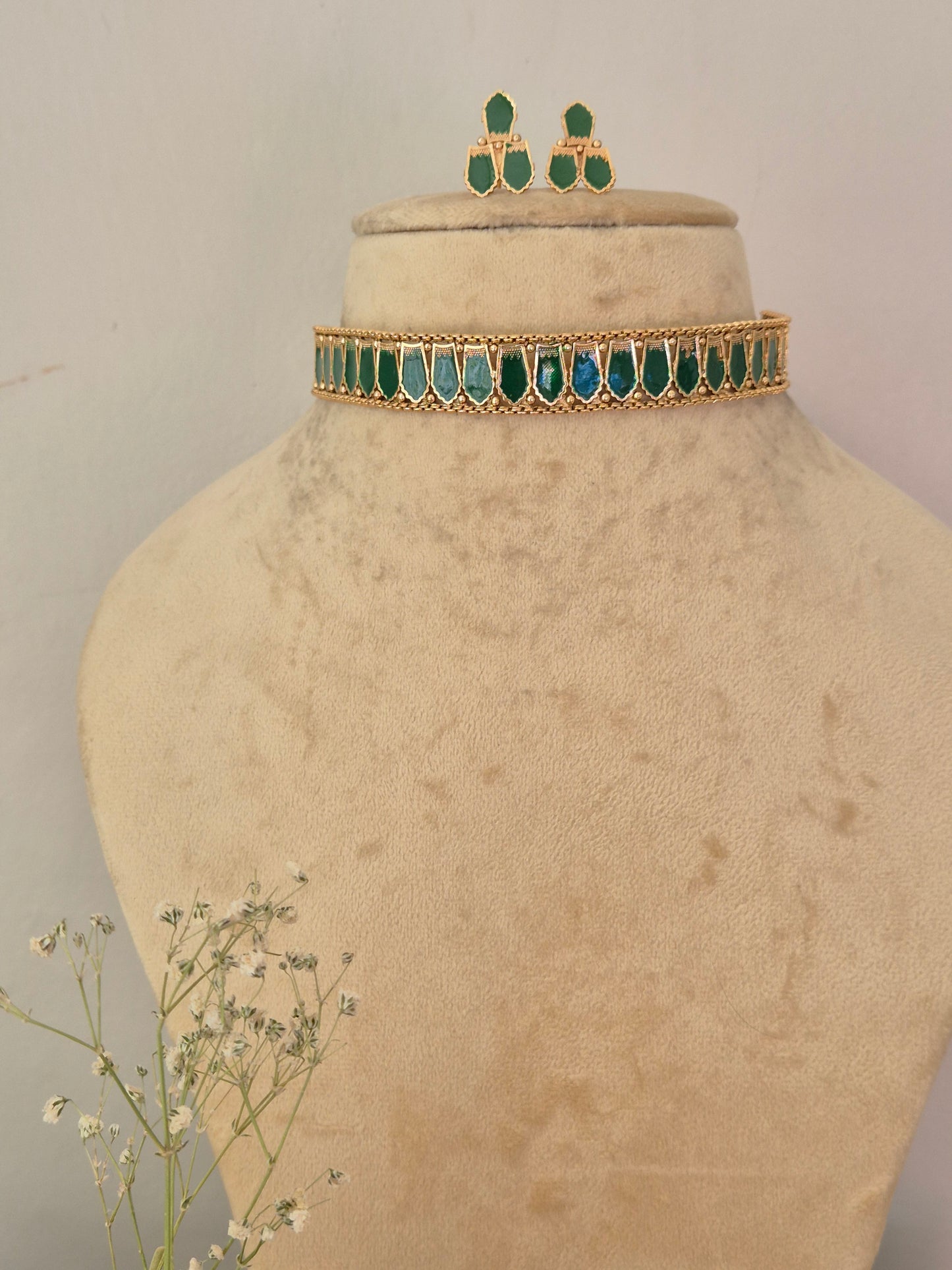 gold-toned traditional Indian choker necklace and matching drop earrings decorated with vibrant green marquise-cut stones, by naitri.in