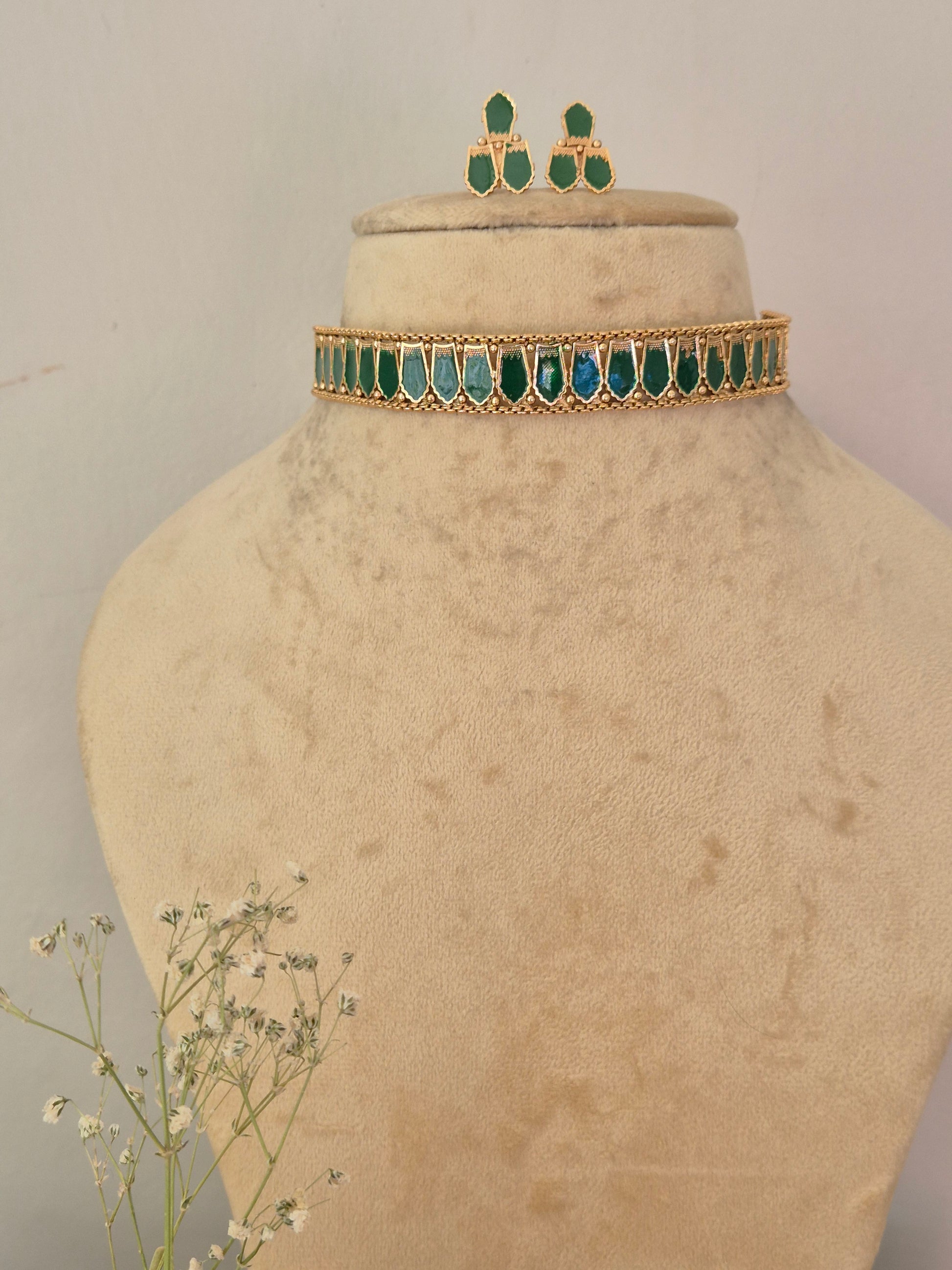 gold-toned traditional Indian choker necklace and matching drop earrings decorated with vibrant green marquise-cut stones, by naitri.in