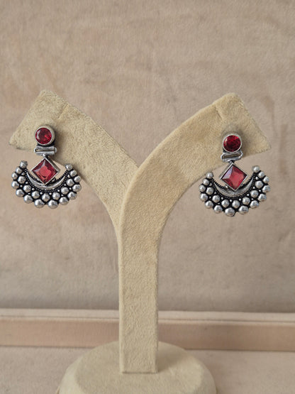 Handcrafted oxidized silver drop earrings with pinkish-red gemstone Modern Indian aesthetic silver-plated statement earrings featuring a vibrant red square-set stone and delicate metallic bead detailing by naitri.in