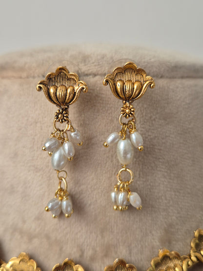 Gold earrings with pearl-like beads hanging attached by flower shaped eaarings by naitri.in