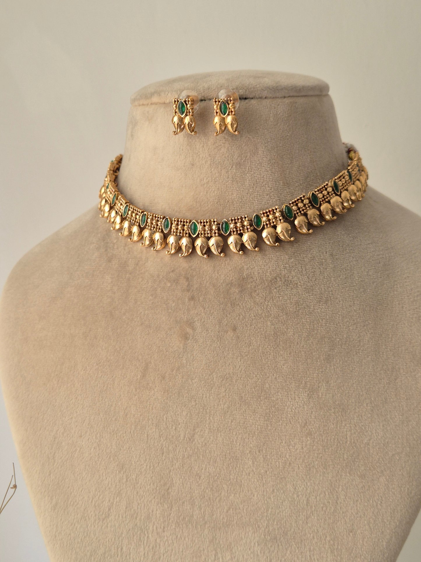 minimal Gold necklace leaf designed and some green stones are attached with chain same with earrings by naitri.in 
