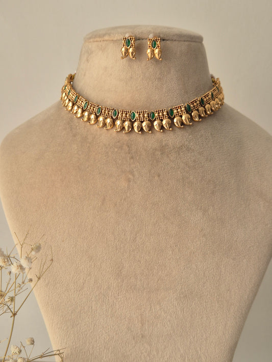 Gold necklace with leaf drop design attached fir gold plated chain and green stones attached in chain same designed earrings by naitri.in